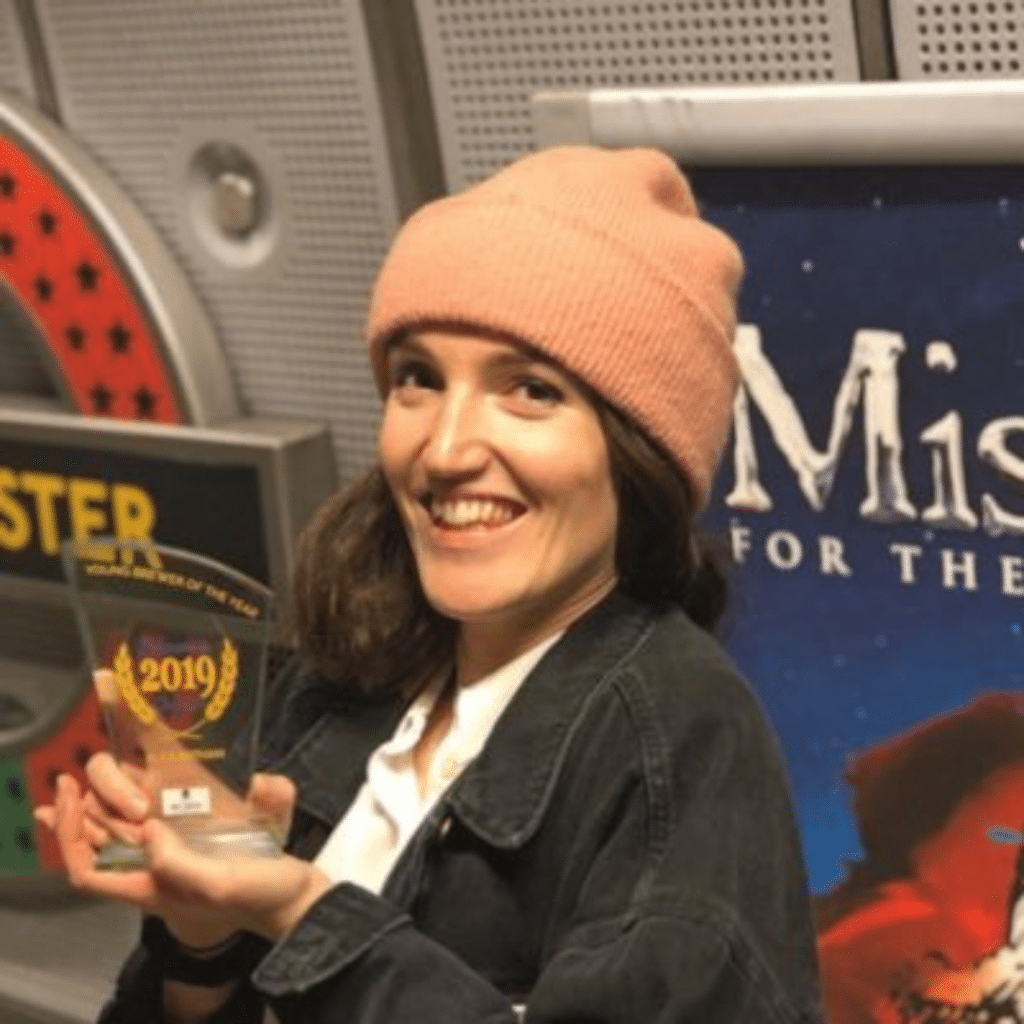 This image features Head Brewer Alice Bathem from Bathem's Brewery, star guest on Spreading Hoppiness. In this image she is smiling while holding a brewing award trophy.