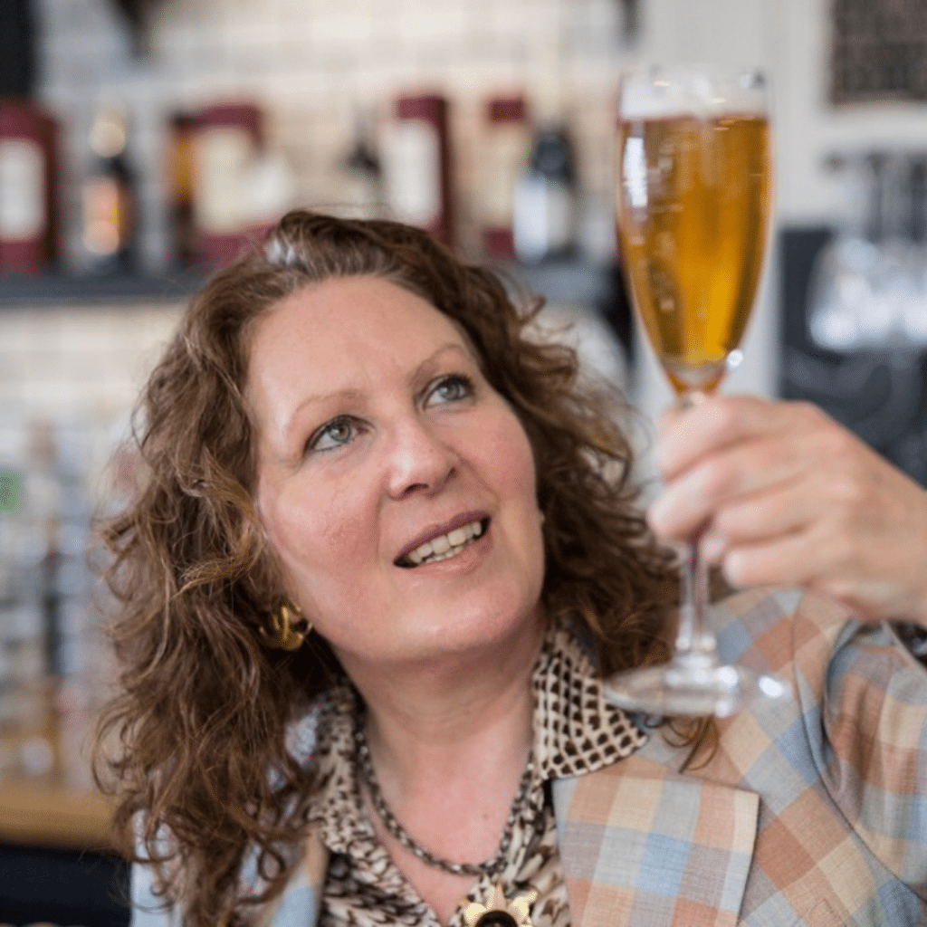 This image Beer Sommelier Jane Peyton star guest on Spreading Hoppiness. In this photo she is smiling while looking at a glass of beer.